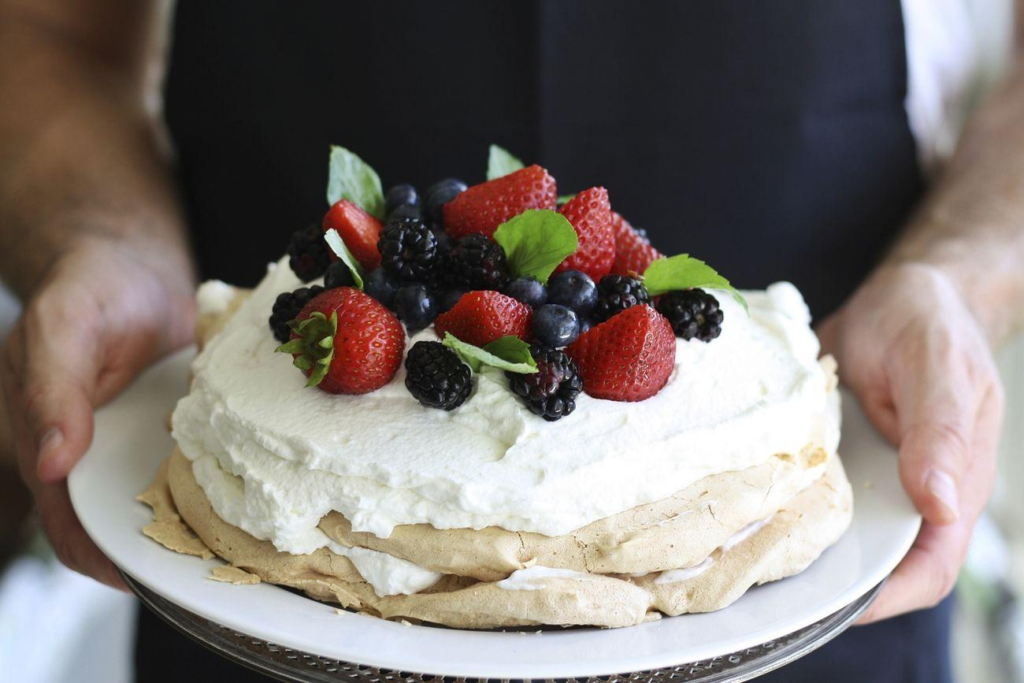 An image of a pavlova with berries as garnishing.