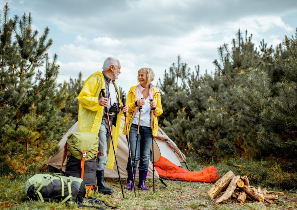 Senior couple on a camping adventure, both holding a walking stick. 